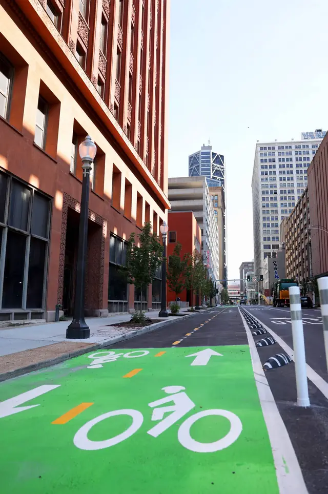 7th Street in downtown St. Louis after Raineri's street improvements: a green bike lane, bollards and new curb beside a historic brick building