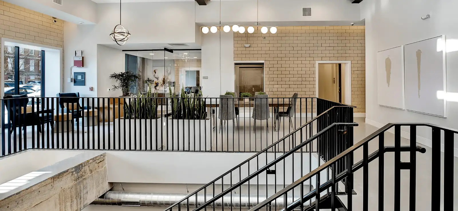 A finished brick and glass atrium lobby with a black steel stair rail, built by Raineri